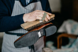 HOMME BROSSANT UNE CHAUSSURE AVEC UN DECROTTOIR